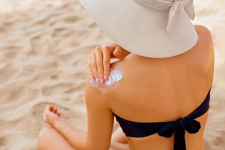 Woman applying sunscreen to her shoulder.